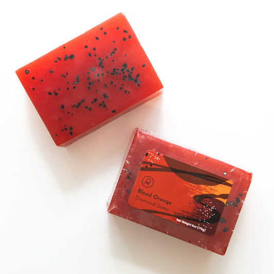 Red soap bar with black specks and its packaging on a white background